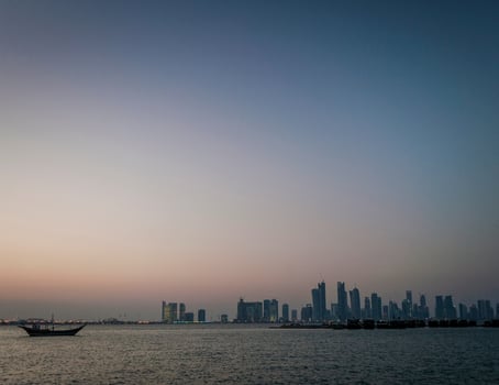 Doha city skyscrapers urban skyline view and dhow boat in Qatar photo