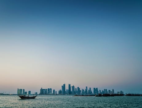 Doha city skyscrapers urban skyline view and dhow boat in Qatar photo