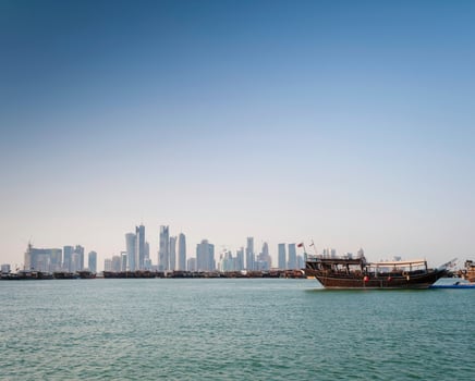 Doha city skyscrapers urban skyline view and dhow boat in Qatar photo
