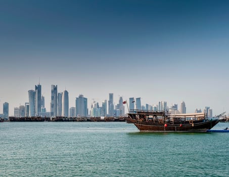 Doha city skyscrapers urban skyline view and dhow boat in Qatar photo