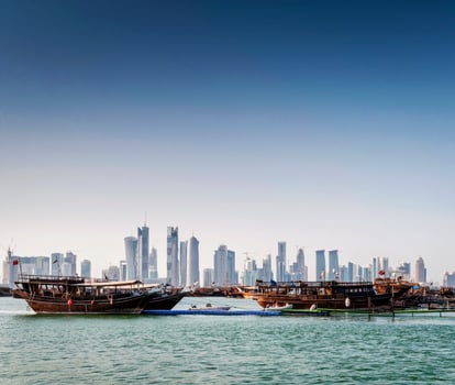 Doha city skyscrapers urban skyline view and dhow boat in Qatar photo