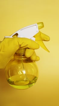 Hand in yellow rubber glove holding plastic spray photo