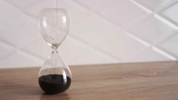 Crystal hourglass with black sand on wooden table photo