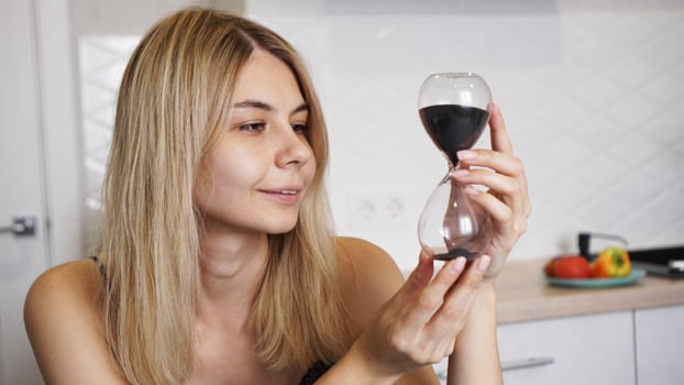 Woman looks at the hourglass and smiles, time concept photo