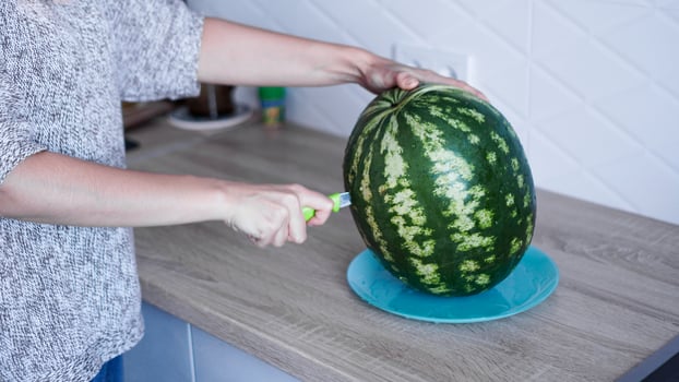 Closeup of woman hand cutting watermelon in the kitchen photo