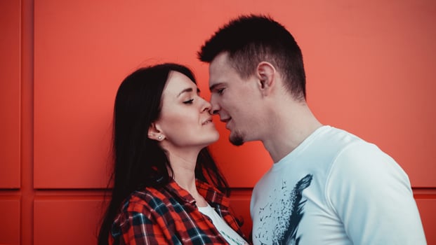 Couple kissing against isolated red wall in the city photo
