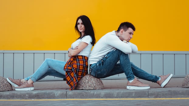 Confused young couple standing with one anothers back photo