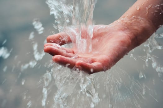 Hand catches water drops coming out of faucet photo