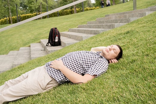 Young thoughtful man sitting on the grass in the park photo