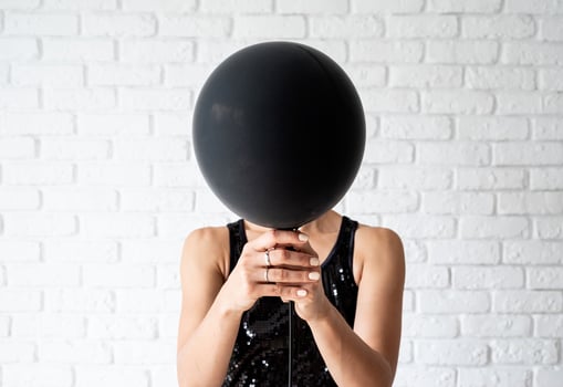 Woman in black dress holding black balloon in front of her face photo