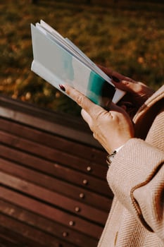 Woman in an autumn coat holds a book. Autumn park photo