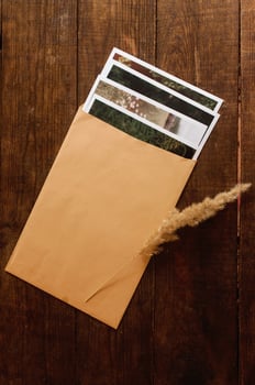 Photos are enclosed in a beige envelope, located on a brown wooden table