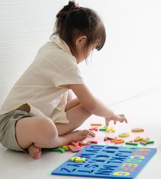 Little girl playing with an alphabet puzzle photo
