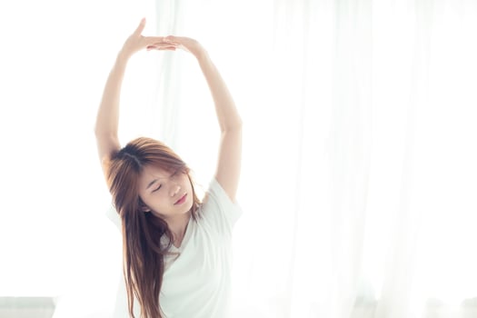 Young Asian woman stretch and relax in bed. photo