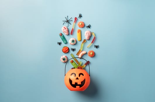Halloween sweets and candies in a pumpkin pot, top view on blue background photo