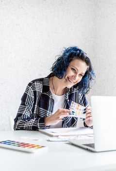 Designer working with colour palettes and laptop in her studio photo