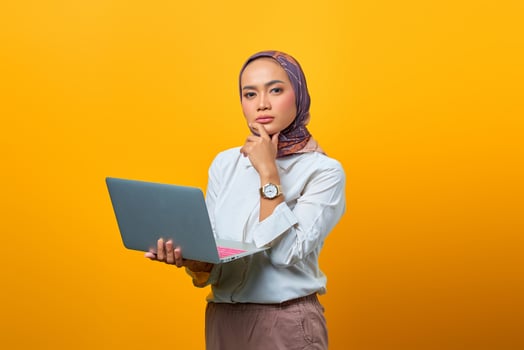 Portrait of confident Asian woman holding laptop and looking at camera photo