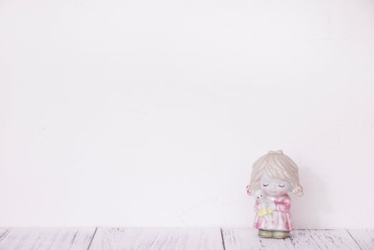 Ceramic doll on white wall photo