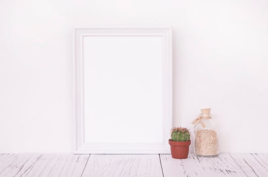 White frame with plant and bottle photo