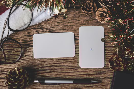 A blank card, glasses and a pen is placed on wood. photo