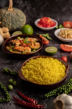 Turmeric rice in a brown cup with spices on black cement. photo