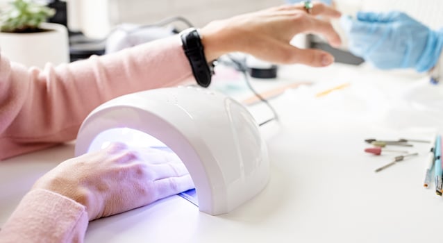 Woman in manicure salon drying her nails in a UV lamp photo