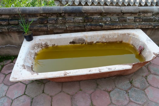 Desert broken bathtub with dirty water inside photo