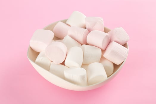 Marshmallow in bowl on pastel pink background photo