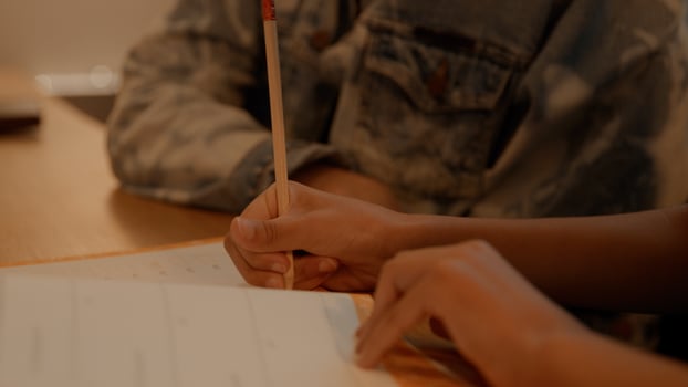 Woman helping girl doing homework at table photo