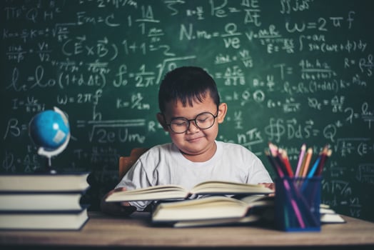 boy reading a book sitting at the table in the classroom photo