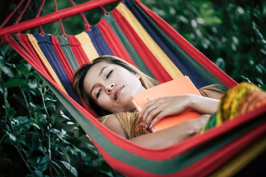 Young woman reading a book lying in a hammock photo
