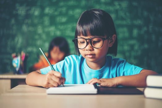 girl with crayon drawing at lesson in the classroom photo