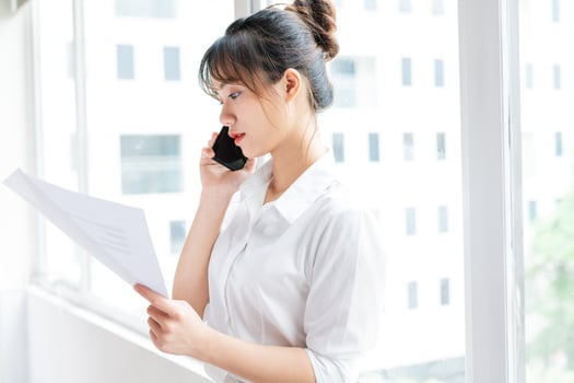 Portrait of young businesswoman standing by the window and making phone calls with her partner photo