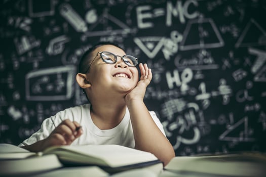 A boy with glasses man writing in the classroom photo