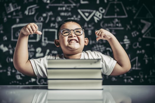 A boy with glasses sitting in the study and with both arms perpendicular photo