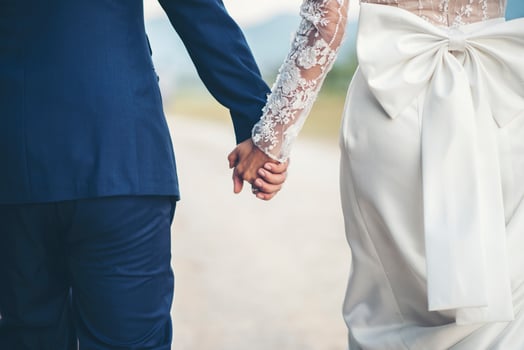Close up of married couple holding hands in wedding day photo