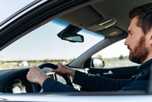 View from the street of the handsome businessman driving car before buying. Attractive elegant man in business closes driving car. Transportation concept photo