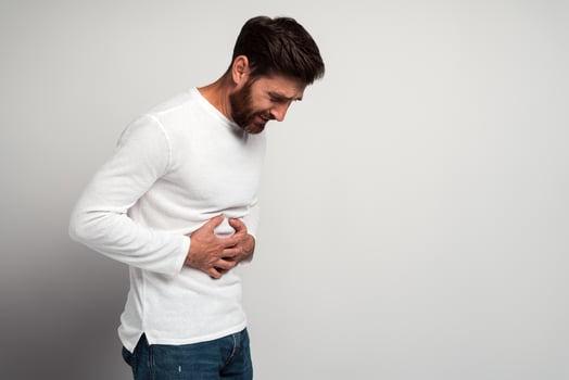 Young man having a stomachache. Young man keeping hands at his stomach because painful disease feeling unwell. Ache concept photo
