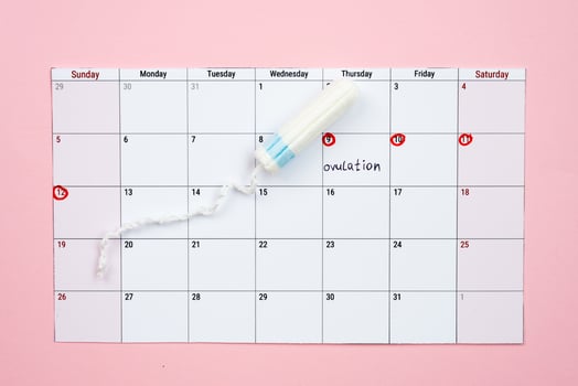 Menstrual calendar and woman  tampon lying on pink background. - Image photo