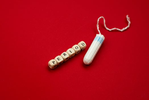 Tampon lying isolated on red background with text period. Concept women sanitary protect photo