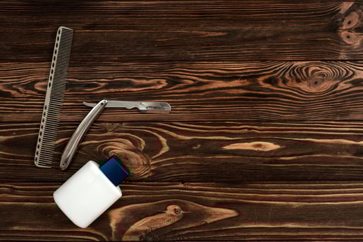 Comb, metal shaving razor, cream jar on the wooden background photo