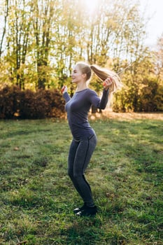 Pretty, slim girl jumping on skipping rope outdoors photo