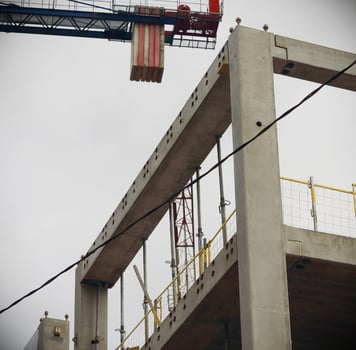 Construction crane over concrete building carcass on white sky photo