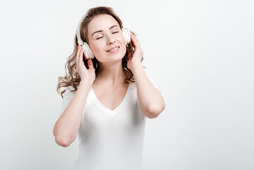 Cute girl in a white T-shirt listens to music in headphones on a white wall background photo