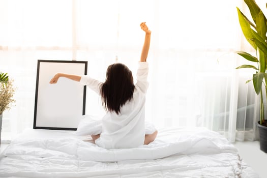 Asian woman Beautiful young smiling woman sitting on bed and stretching in the morning at bedroom after waking up in her bed fully rested and open the curtains in the morning to get fresh air. photo
