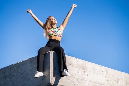 Young woman opening arms against blue sky photo