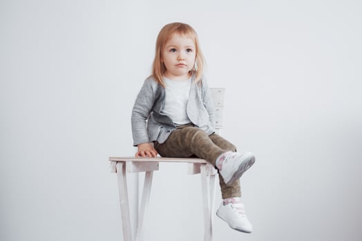 A young child, a little girl sitting on a tall stool laughing photo