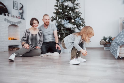 Merry Christmas and Happy New Year Beautiful mom, dad and daughter are using a laptop and smiling while sitting near Christmas presents photo