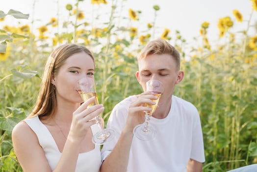 Young couple having picnic on sunflower field at sunset photo