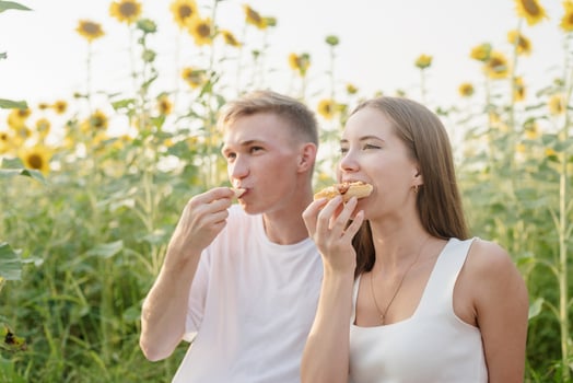 Young couple having picnic on sunflower field at sunset photo
